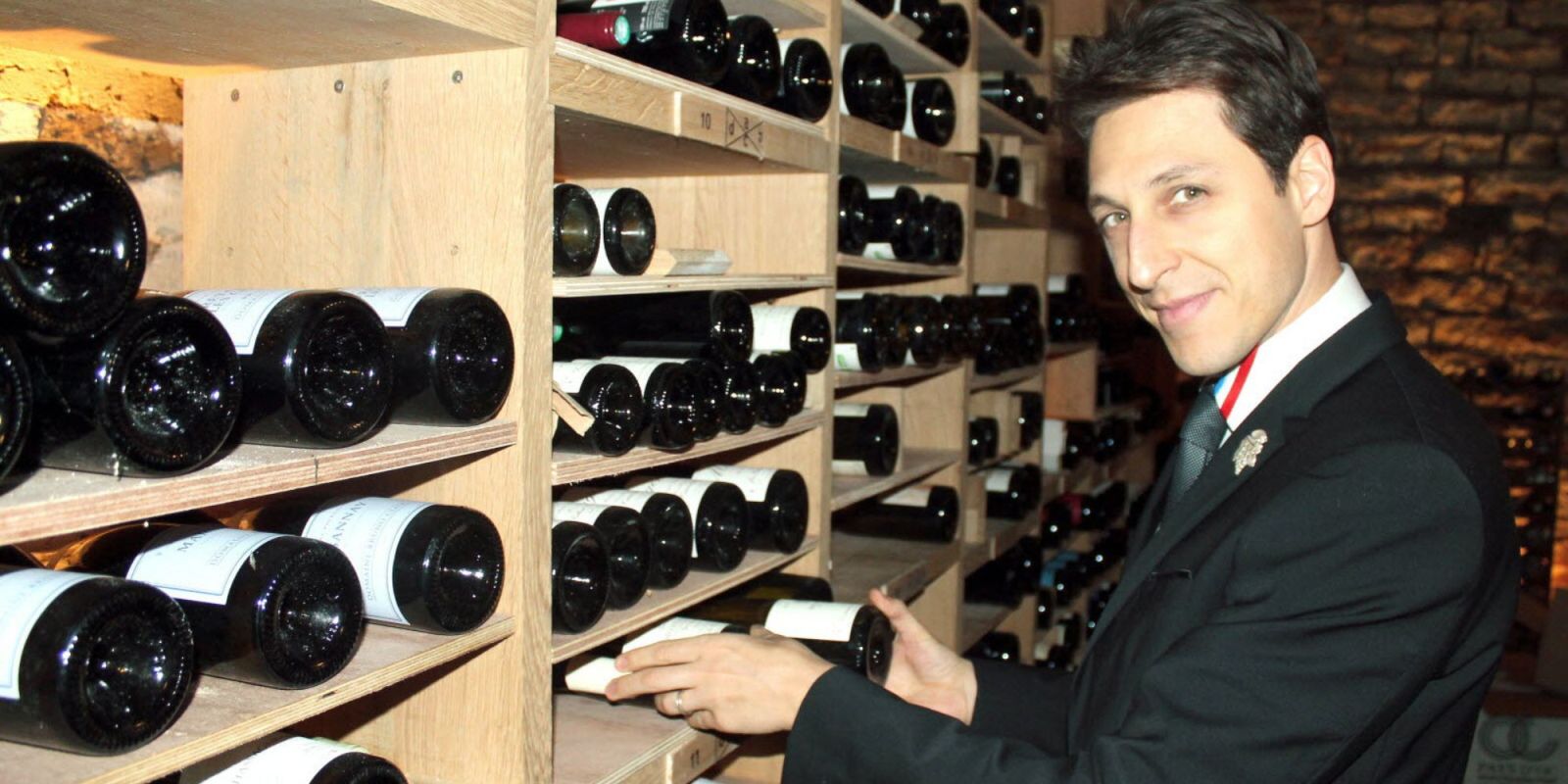 Winemaker carefully inspecting a bottle in a dimly lit Jura wine cellar, symbolizing precision and tradition in French winemaking